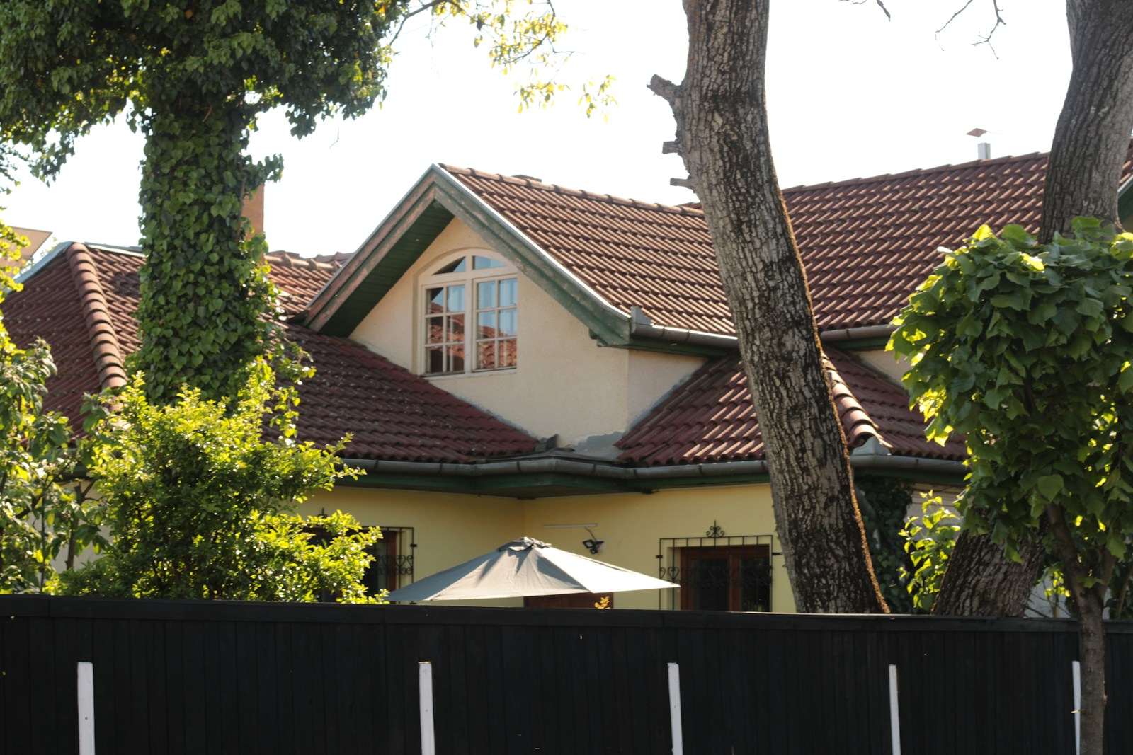 a house with a fence and trees in front of it